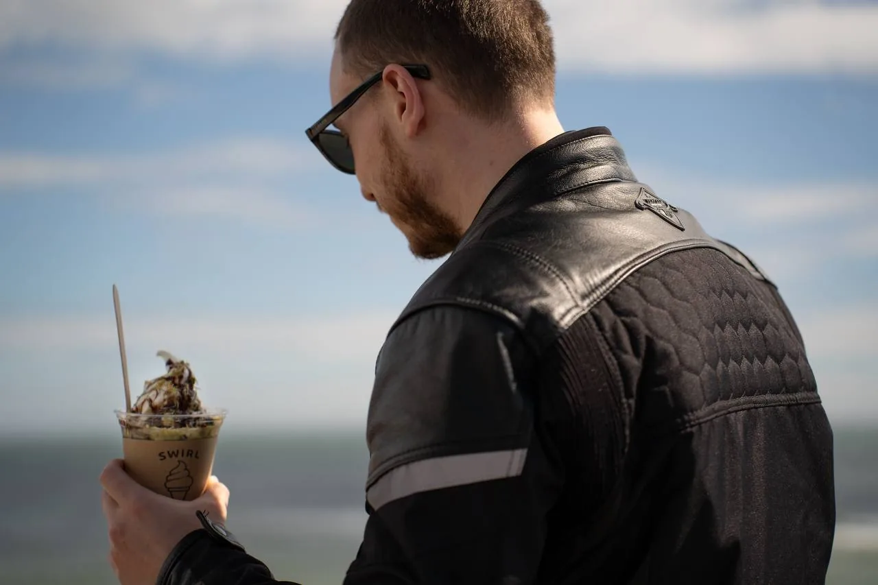 Strawberry sundae cup held on the grass by the sea