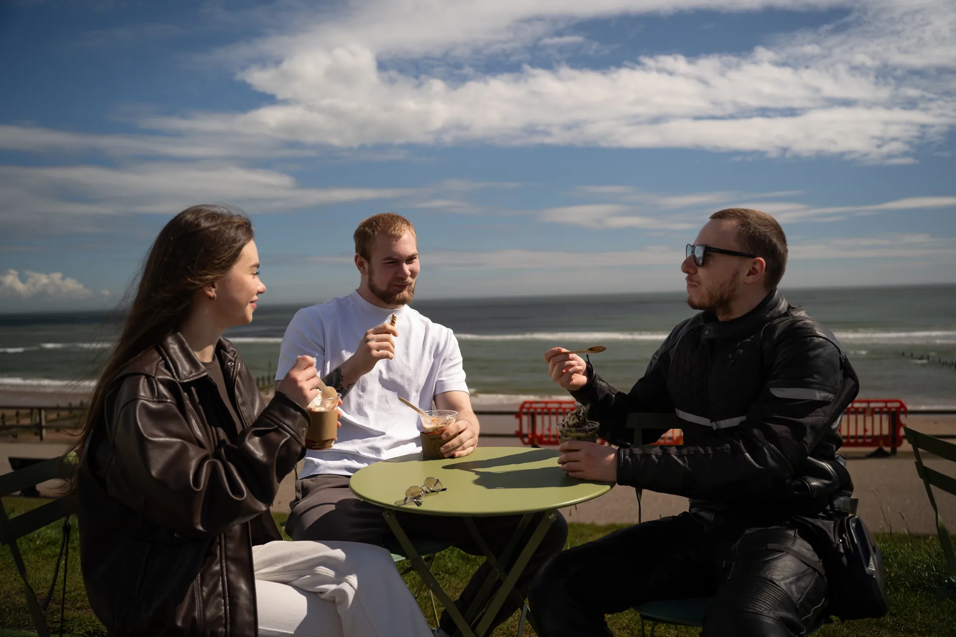 Friends enjoying ice cream at a table by the sea
